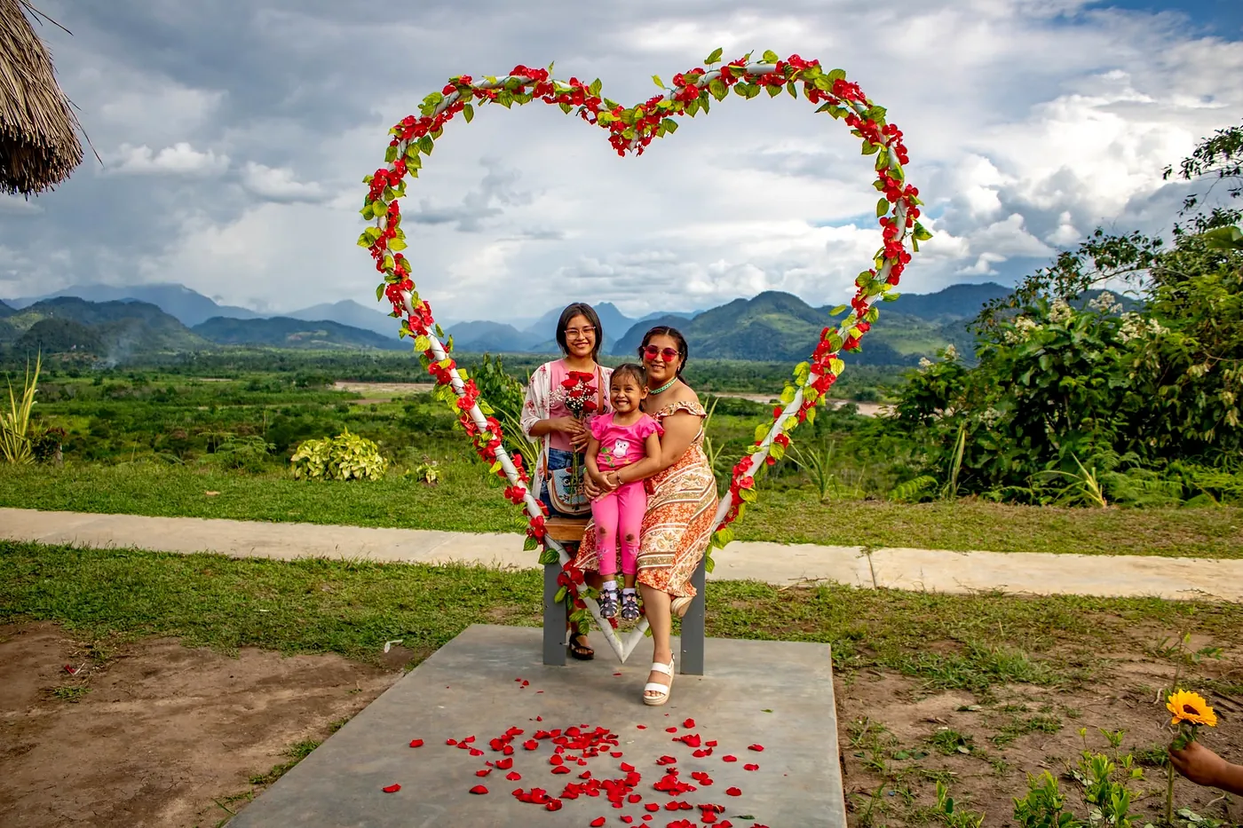 Familia posando dentro de un corazón decorado con flores frente al paisaje de Tingo María